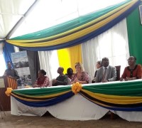 A man makes an announcement by the head table where 7 people are seated