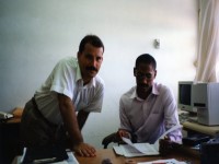 Standing DevPar consultant assesses documents with committee member seated at computer