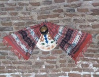 a striped scarf and ceramic disc decorate a brick wall