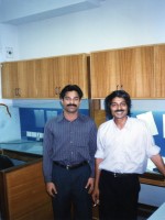 2 smiling men stand in the office cubicle