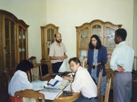 3 people stand and 2 sit as they work together around a table