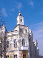 A corner building of yellow stone with white trim and the Moldovan flag