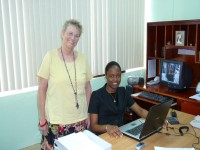 A female DevPar representative stands by a woman seated at her computer in the Ministry of Finance of Belize